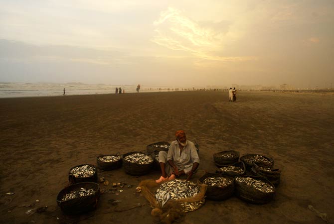 Noor Jan, a fisherman waits for customers at to sell his catch. ? Photo by AP