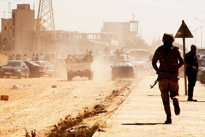 Members of the National Army make their way to the gates of pro-government Rafalla al-Sihati brigade after demonstrators attacked the brigade's base.