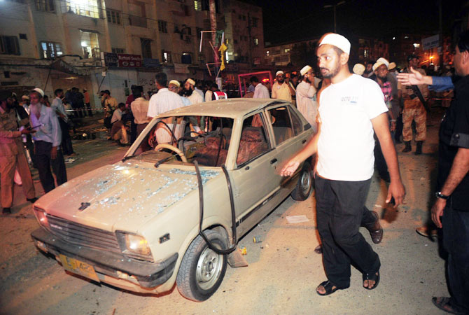 Local residents gather at the site of a bomb explosion in Karachi on September 18, 2012.