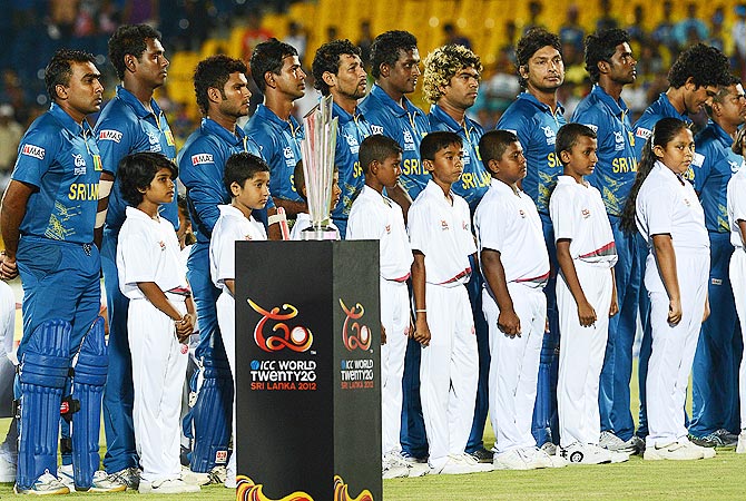 The Sri Lankan cricket team with school pupils listen to the national anthems before the start of the first ICC Twenty20 Cricket World Cup match between Sri Lanka and Zimbabwe at The Mahinda Rajapaksa International Cricket Stadium in Hambantota. -Photo by AFP