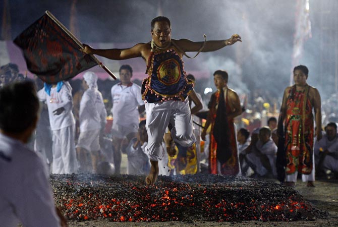 A devotee of Chinese Jui Tui shrine walks on live coals during a ceremony marking the annual Vegetarian Festival. During the festival, which begins on the first evening of the ninth lunar month and lasts nine days, religious devotees slash themselves with swords, pierce their cheeks with sharp objects and commit other painful acts to purify themselves, taking on the sins of the community. ?AFP Photo