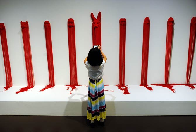 A child takes photos of artwork during a preview visit to The China Art Museum. ? Photo by AFP
