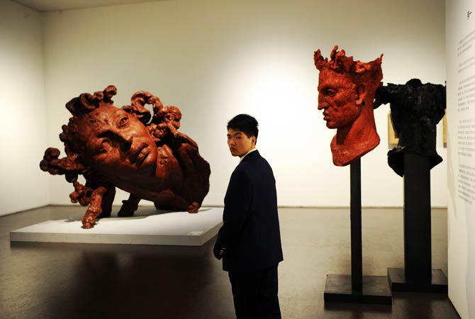 A security guard stands near sculptures during a preview visit. ? Photo by AFP