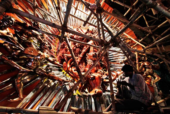 An artist sits on a bamboo scaffold while working on an idol of Hindu Goddess. ? Photo by AP