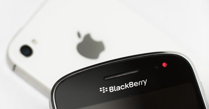 File of A Research in Motion BlackBerry smartphone handset is reflected in the logo of an Apple iPhone in this illustration picture taken in Lavigny