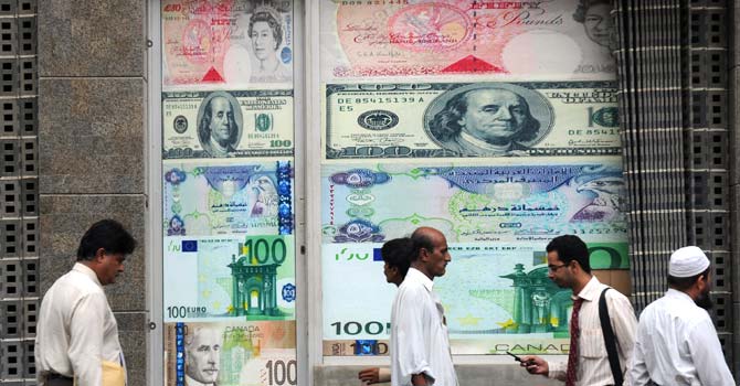 money_exchange3-670 Pedestrians walk past a currency exchange shop in Karachi. NADRA's remittance programme will enable NADRA centres to process inward home remittances from overseas for the general public using smart national identity cards. – File photo by AFP