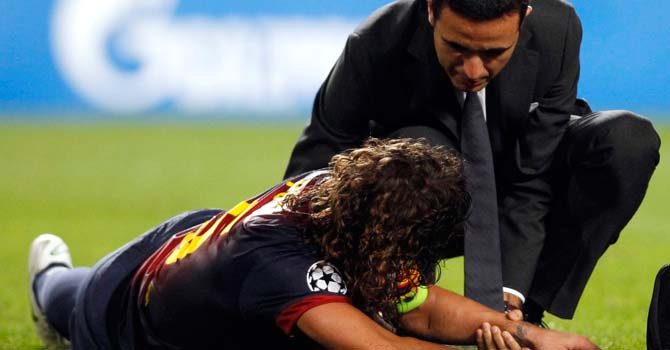 puyol-barca-benfica-reut-670 Barcelona's Carles Puyol (L) receives assistance after falling and sustaining an injury during their Champions League Group G soccer match against Benfica at the Luz stadium in Lisbon – Photo by Reuters