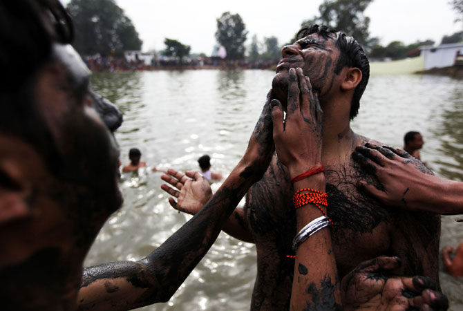 Indian Hindu devotees smear themselves with mud before taking a holy dip during the annual farmers fair at Shama Chak Jhiri, some 22kms from Jammu on November 28, 2012. ? Photo by AFP