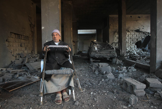 A Palestinian man sits amid the rubble in his bombed house following an Israeli air strike. - Photo by AFP