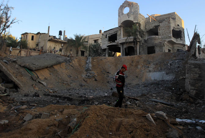 A Palestinian youth walks amid destruction following an Israeli air strike.