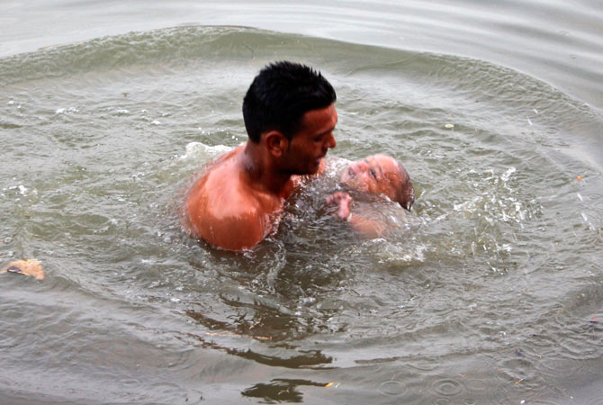 A Hindu devotee holds his son while dipping him into a holy pond during the annual Jhiri Fair at Kanachack village on the outskirts of Jammu, India, Wednesday, Nov. 28, 2012. ? Photo by AP