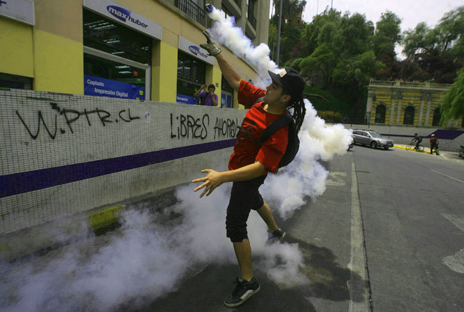 A student protester throws a tear gas canister as they clash with riot police officers during a rally demanding that the government makes changes to the public state education system in Santiago.?Photo by Reuters