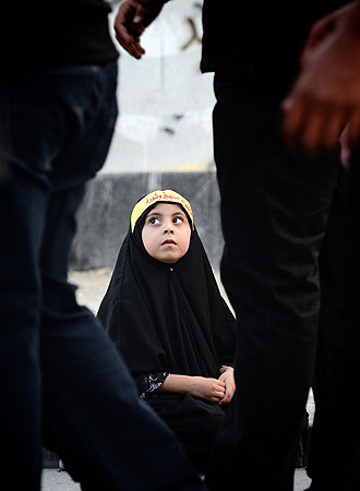 A Bahraini Shiite Muslim girl with a banner on her head participates in a ceremony marking Ashura. Arabic writing on banner reads "Ashura is an approach and revolution". ?Photo by AFP