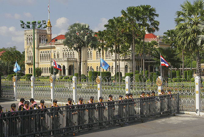 Thai policemen guard in front of fense set up to block the way in Government House in Bangkok. Anti-government protesters are expected to show up in Bangkok on Saturday to demand an overthrow of the current government under the rule of Prime Minister Shinawatra.?Photo by AP