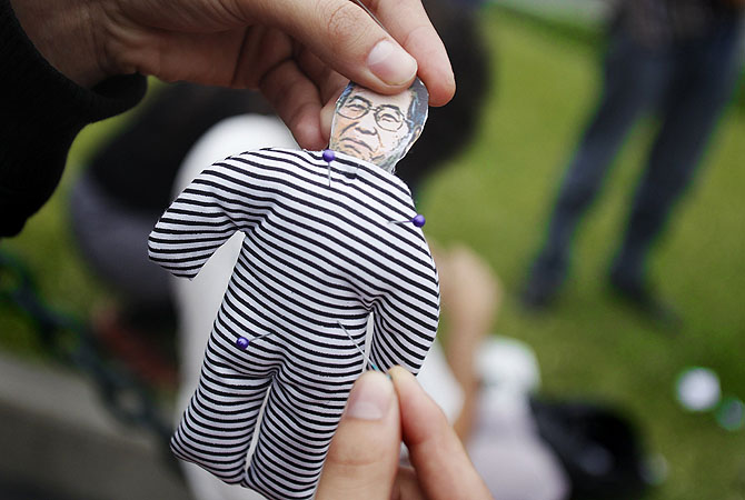 A protester sticks a pin into a voodoo doll of Peru's former president Alberto Fujimori during a protest in downtown Lima. Fujimori, currently in prison for human rights crimes and suffering from oral cancer, has asked President Ollanta Humala for a humanitarian pardon.?Photo by Reuters