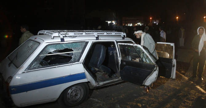 A man checks a damaged car at the site of a blast which took place near a Shi'ite procession in Sanaa