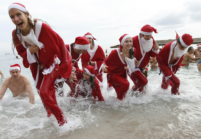 People dressed up as Santa Claus enjoy a traditional Christmas bath on December 23, 2012 in Monaco. ? Photo by AFP