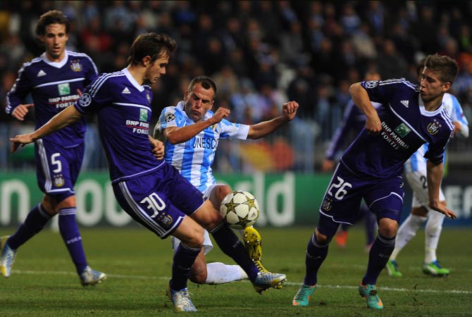 Malaga's Portuguese midfielder Duda vies with Anderlecht's Belgian midfielder Guillaume Gillet (Left) and Belgian midfielder Dennis Praet (Right) during the UEFA Champions League Group C football match Malaga CF vs RSC Anderlecht at La Rosaleda stadium in Malaga.