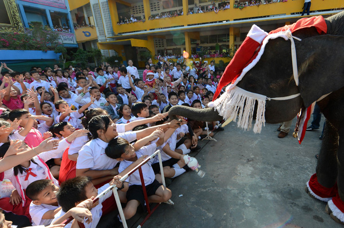 An elephant dressed in a Santa Claus costume gives gifts to students ahead of the Christmas festival at a school in Ayutthaya province on December 24, 2012. The event was held as part of a campaign to promote Christmas in Thailand. ? Photo by