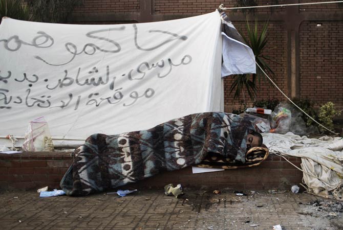 An Egyptian protestor sleeps on the pavement outside the presidential palace in Cairo on December.