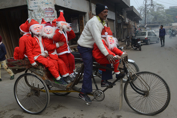Indian schoolchildren dressed as Santa Claus ride on a cycle-rickshaw through a street in Amritsar on December 24,2012, ahead of Christmas Day. Despite Christians forming a little over 2 percent of the billion plus population in India, with Hindus comprising the majority, Christmas is celebrated with much fanfare and zeal throughout the country. ? Photo by AFP