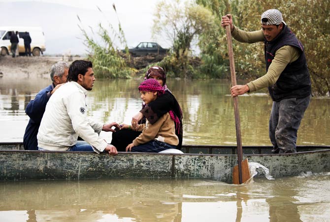 Members of a fleeing Syrian family huddle together aboard a boat that will take them across the Orontes river to Turkey.