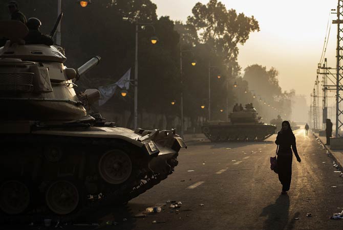 Egyptians walk past a line of army tanks stationed outside the presidential palace in Cairo.