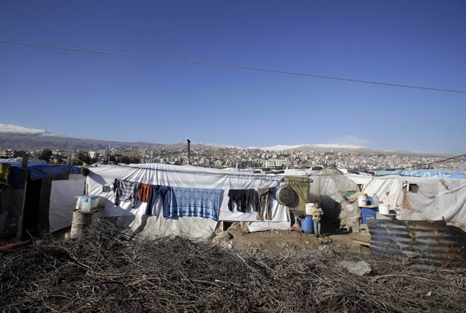 A Syrian refugee girl stands outside of her makeshift house built on an agricultural field in Saadnayel in the Lebanese Bekaa valley.