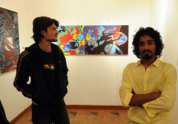 Artists Qadir Jhatial (L) and Tahir Ali pose with their paintings during an exhibition at the Rohtas Art Gallery in Islamabad. – AFP