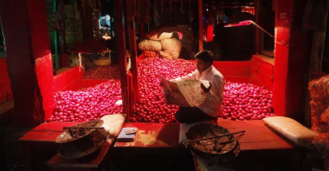 A vendor reads a newspaper at a wholesale vegetable market in Kolkata on Dec 14, 2012. India's wholesale inflation cooled to its weakest pace in 10 months in November, a positive sign for the struggling economy but probably not a big enough slowdown to persuade the central bank cut interest rates next week. - Reuters