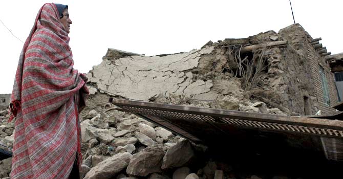 An Iranian woman inspects a destroyed house in the eastern village of Shaj, some 100 kilometres outside the city of Birjand, on December 6, 2012, the day after an earthquake struck eastern Iran, near the Afghan border. – Photo by AFP