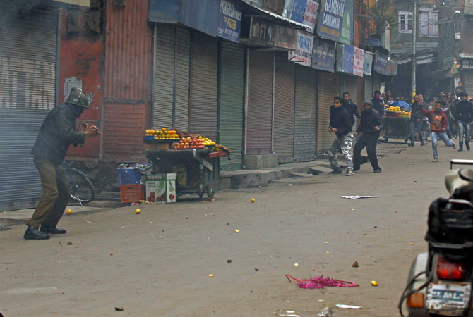 An Indian policeman confronts supporters of the Jammu Kashmir Liberation Front (JKLF) during clashes in Srinagar December 7, 2012.