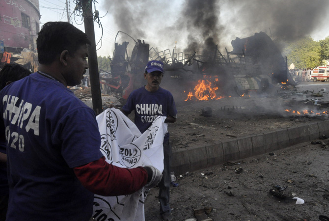 Rescuers carry a sheet to collect a body part at the scene of a bomb explosion in Cantonment area, Karachi December 29, 2012. A bomb went off on a bus in the southern Pakistani city of Karachi on Saturday killing six people and wounding 48, police and a hospital official said.?Photo by Reuters