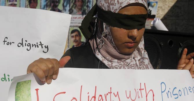 A Palestinian woman who covered her eyes with black ribbons demonstrate in support of Palestinian prisoners held in Israeli jails, some of whom are observing a hunger strike, in Gaza City on Dec 22, 2012. - AFP Photo
