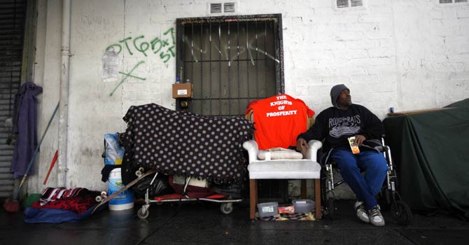 A homeless man sits across the street from where the Skid Row Housing Trust's 102 pre-fabricated 350 square foot modular apartments are under construction downtown, becoming the first housing complex of its type for the homeless in the nation, in Los Angeles, California, Dec 18, 2012. - Reuters