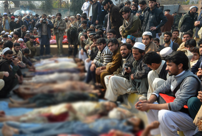Pakistani villagers from the Kyhber Agency gather around the dead bodies of their relatives during a protest in provincial capital Peshawar on January 16, 2013. Demonstrators said gunmen wearing military uniforms stormed homes in Bara Tehsil in Khyber Agency, some 30 kilometers from Peshawar and shot 18 villagers dead in an overnight raid. – Photo by AFP