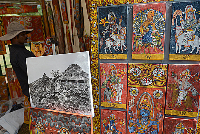 A Sri Lankan artist hangs artwork at the annual painting exhibition known as 'Kala Pola' in Colombo. ? AFP Photo
