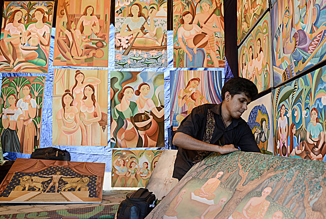 A Sri Lankan artist hangs artwork at the annual painting exhibition known as 'Kala Pola' in Colombo. The annual one-day event is aimed at helping artists sell their paintings in a country where there are only a few galleries where artists can exhibit their work. ? AFP Photo