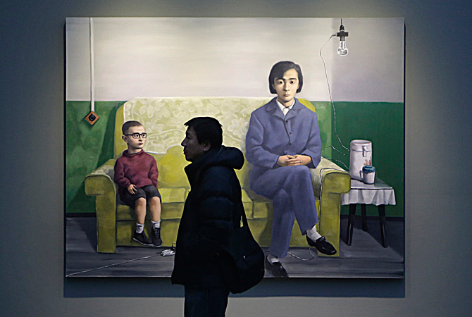 A man walks past an oil painting titled 'My Mother' by Chinese artist Zhang Xiaogang from his "Amnesia and Memory Series", during the Beijing Voice exhibition at Pace Beijing Gallery in Beijing's 798 art zone. Zhang is a 54-year-old painter who has been crowned with many titles, such as "Chinese contemporary art icon" and "China's most expensive living painter". Since the start of his very successful Bloodline - Big Family series in the mid-1990s, Zhang has witnessed and experienced a particular history of China,