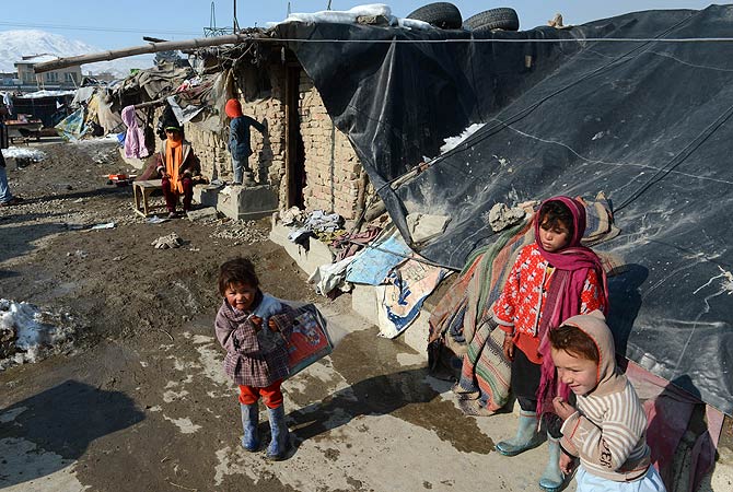 An Afghan child stands outside her tent after she receives winter supplies in Kabul on January 1, 2013. ? AFP Photo