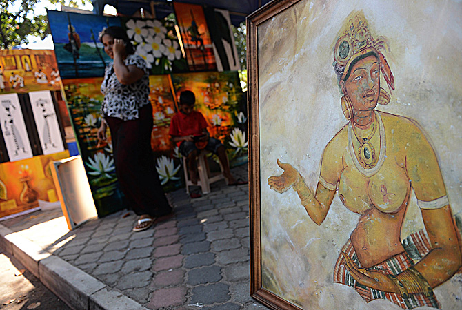 A Sri Lankan woman walks a painting at the annual painting exhibition known as 'Kala Pola' in Colombo ? AFP Photo