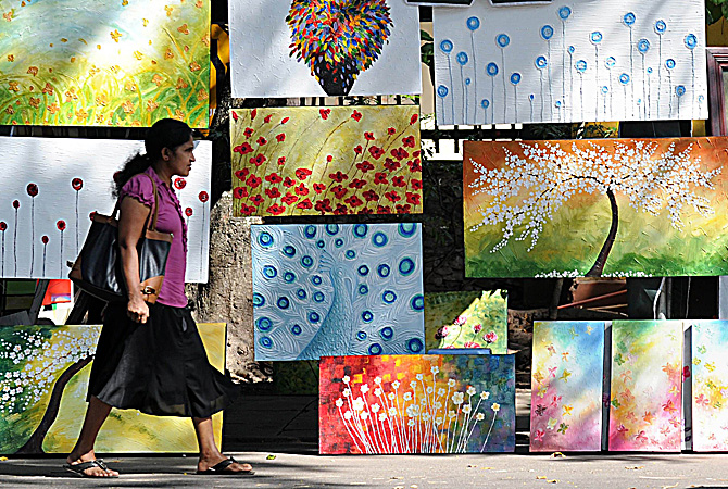 A Sri Lankan woman walks a painting at the annual painting exhibition known as 'Kala Pola' in Colombo ? AFP Photo