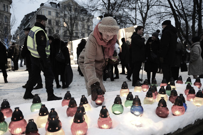 A woman lights a candle as she attends a memorial ceremony, at Raoul Wallenberg Square in Stockholm, Sweden. ?Photo by AFP
