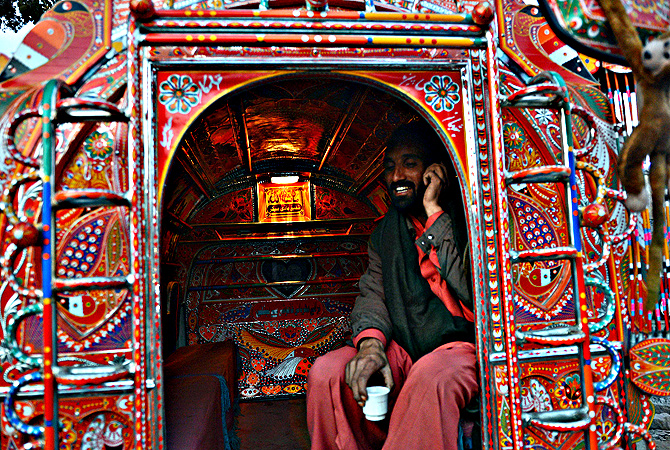 A passenger talks on his phone while travelling in a decorated minivan in Rawalpindi. — AFP Photo
