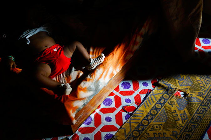 In this Nov 19, 2012 photo, eight-month-old Mohamed sleeps on the family bed as his father, Ibrahim, argues with the family of the boy's mother, Fatmata, after Ibrahim allegedly helped his new girlfriend beat up Fatmata, in Freetown, Sierra Leone. Domestic violence is a problem all over West Africa. ?Photo by AP