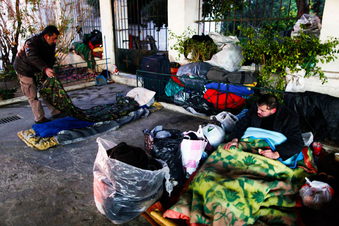 Homeless men prepare to bed down for the night under a road bridge in the Rouf district of Athens. Greece, which is struggling with its worst financial crisis in decades, suffered freezing temperatures in many parts of the country and snowfall in Athens. Municipal officials have opened temporary shelters for people sleeping in the cold snap. -Photo by AP