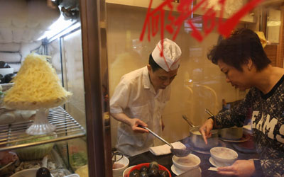 A staff at Ho Hung Kee prepares congee for a customer. —Photo by AFP