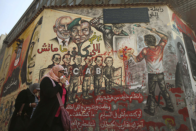 Egyptians walk past graffiti on a wall at Tahrir Square in Cairo.?Photo by Reuters
