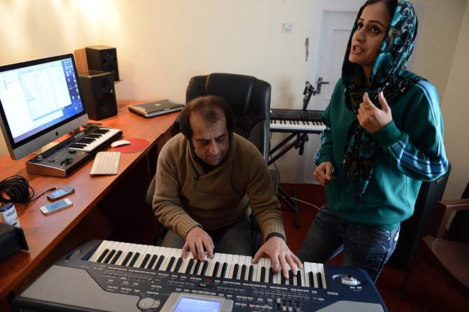Soosan Feroz, 23, (R) Afghanistan's first female rap musician, practices with Afghan pop musician Farid Rastagar at a recording studio in Kabul. – Photo by AFP