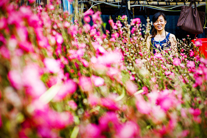 A woman smiles next to blossoms at a Chinese New Year fair in Hong Kong. ?Photo by AFP